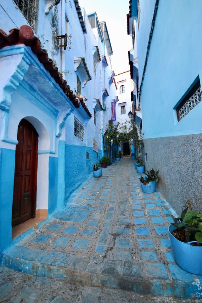 Blue and white buildings line a cobbled street in Chefchaouen