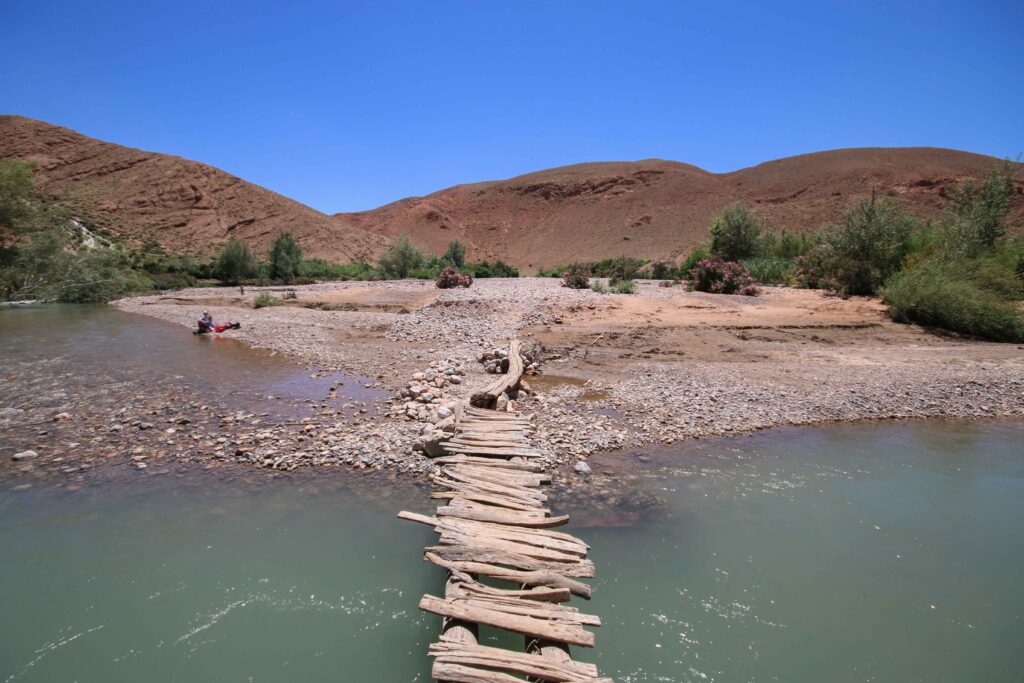 A wooden bridge leads across a river in Dades Gorge, Morocco