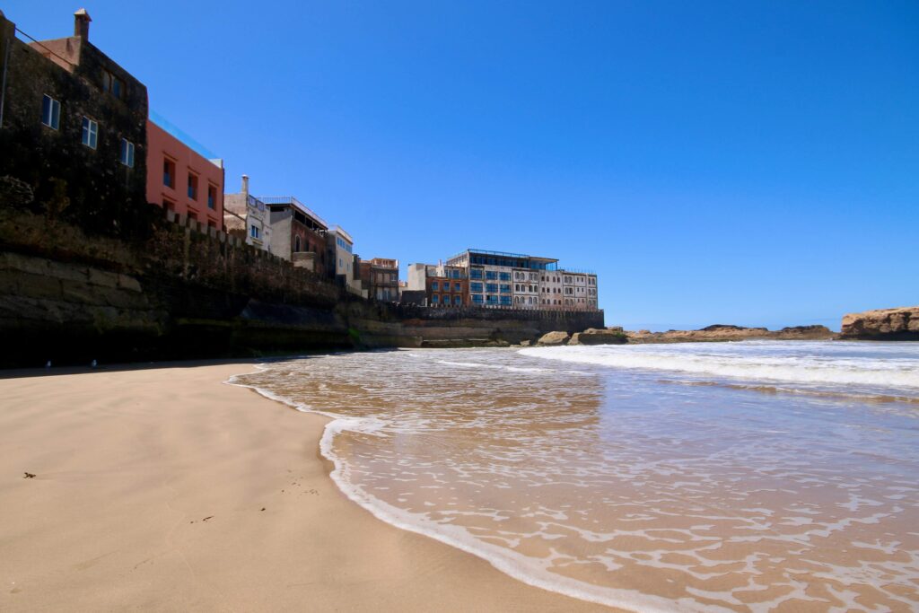 Water laps at the base of Essaouira's ancient medina walls at Plage Akskis