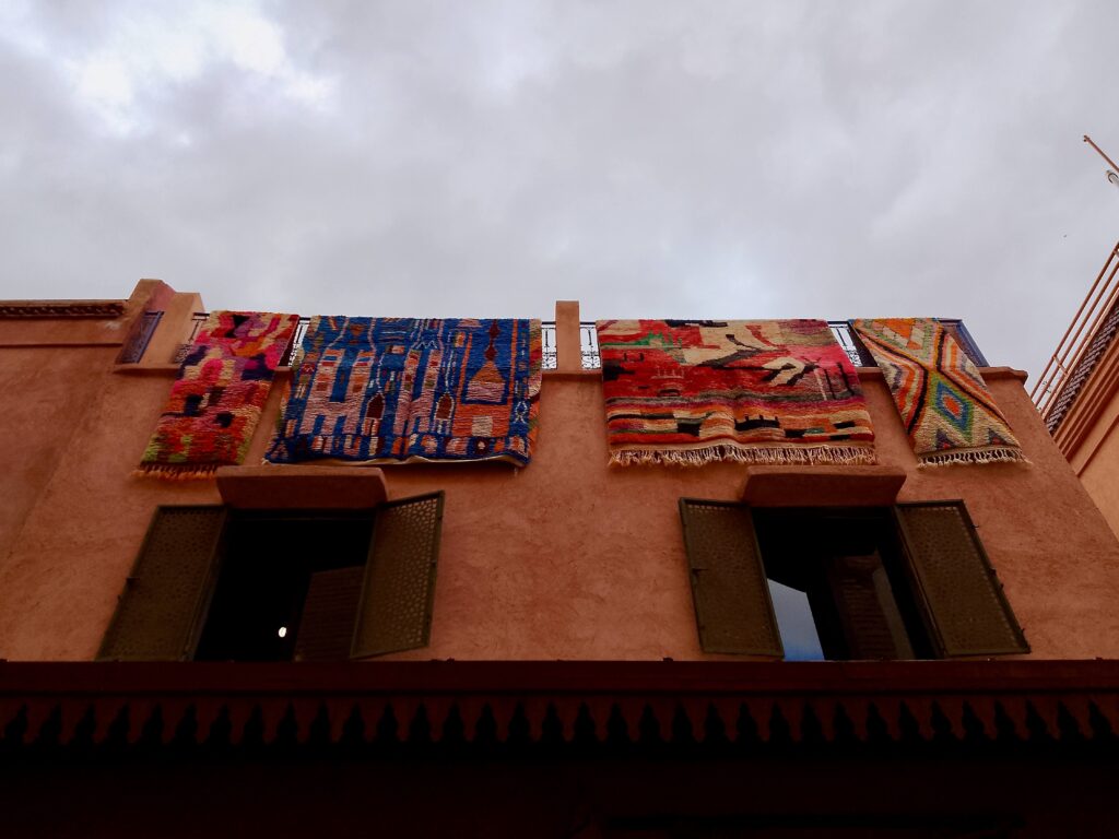 Colourful rugs hanging over an ochre building in the Marrakech medina