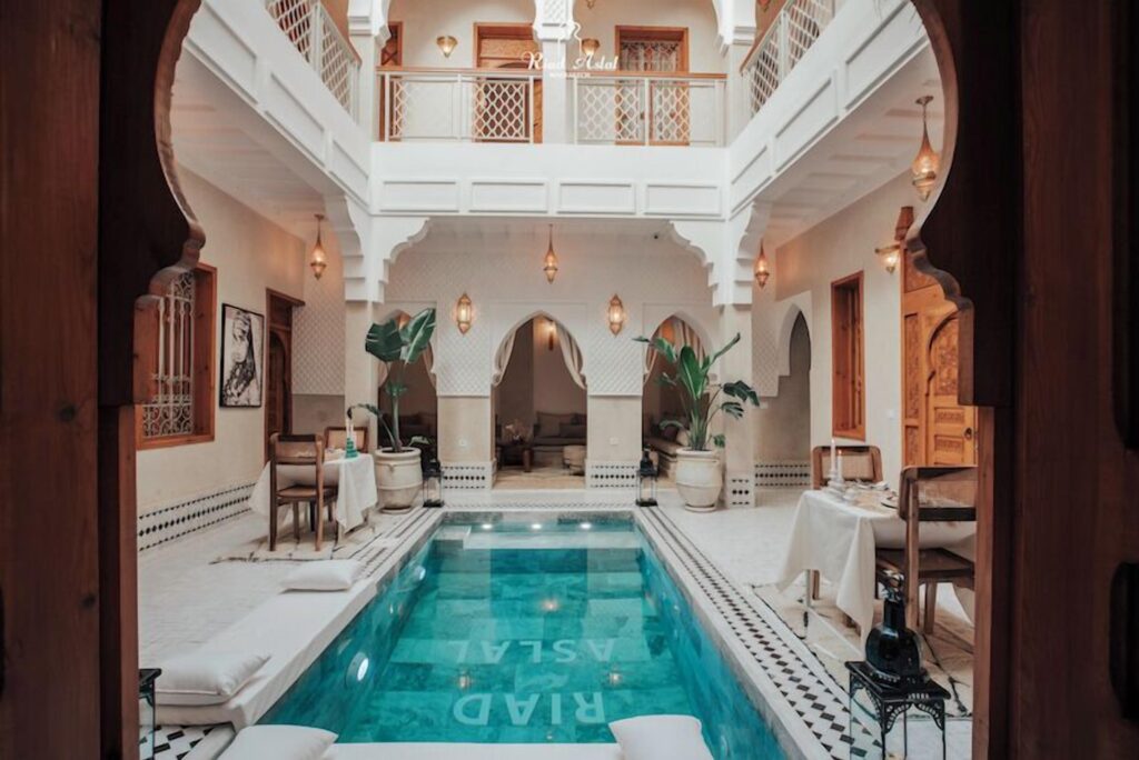 An arch frames the interior courtyard and swimming pool of Riad Aslal in Marrakech