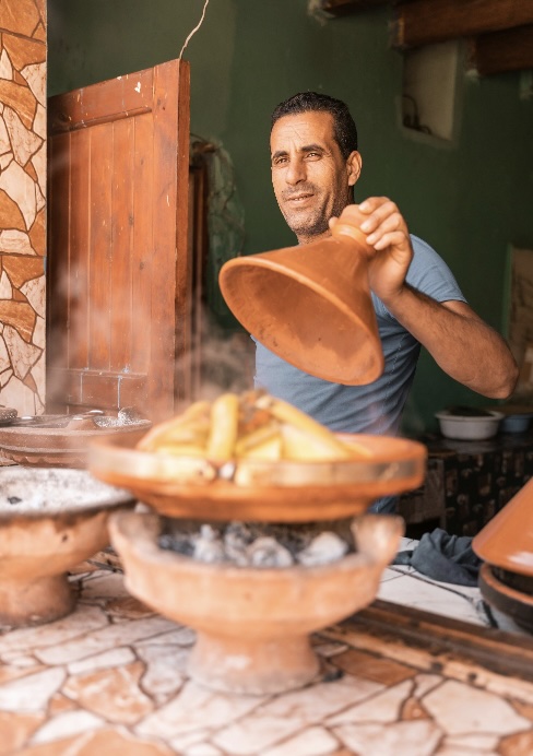 A Moroccan man shows off a slowly cooking tagine