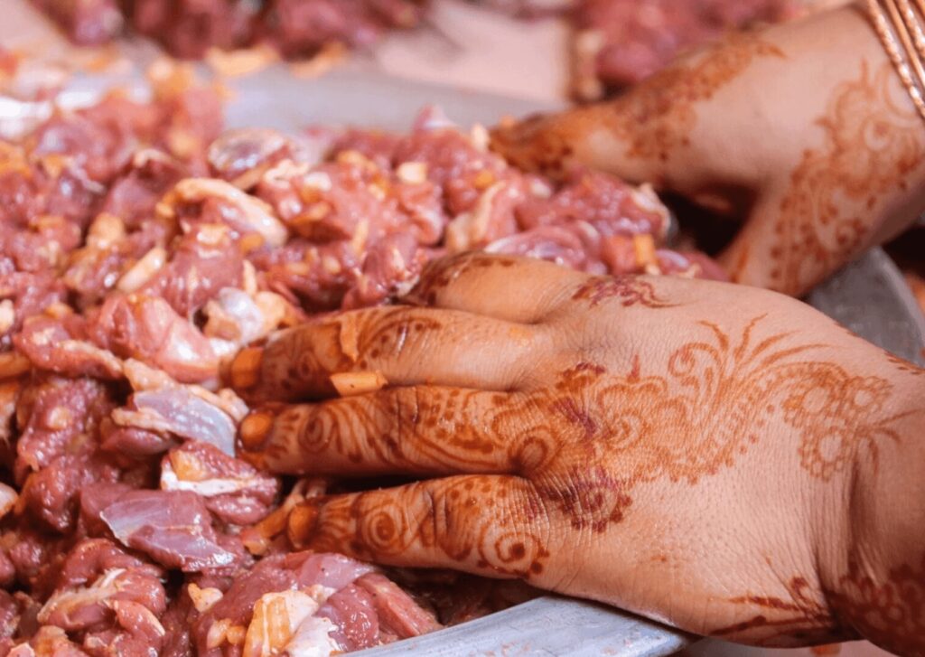 A woman prepares meat with hennaed hands during a traditional Moroccan cooking class
